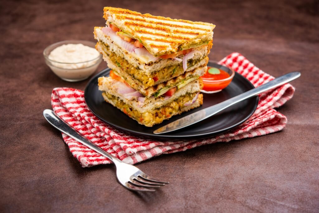 Delicious stacked vegetable grilled sandwiches on a plate with sauces and fork on a napkin.