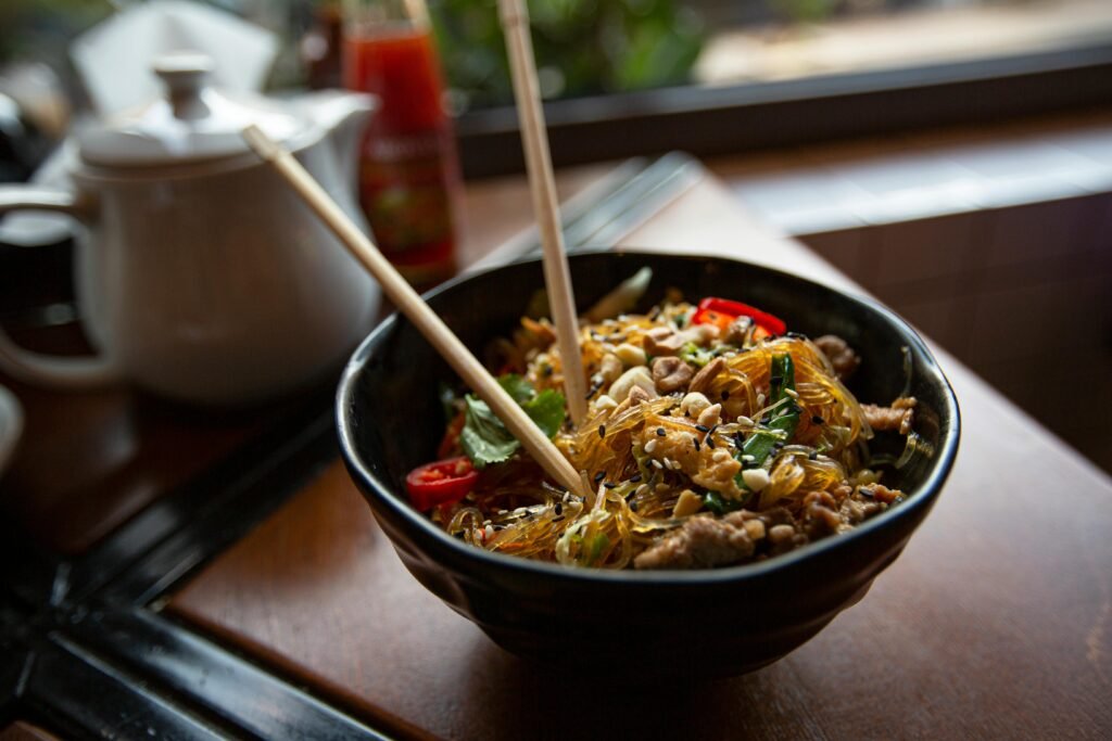 Tasty Asian noodle dish served with fresh herbs and chili peppers in a cozy dining setting.
