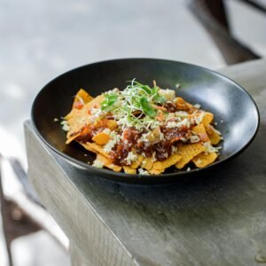 Tasty Mexican nachos topped with vegetables and cheese served on a rustic table.