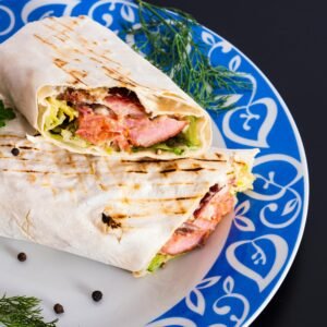 Delicious grilled chicken wrap with fresh vegetables served on a colorful plate.