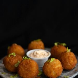 Crispy fried cheese balls served with a creamy dipping sauce on a plate.
