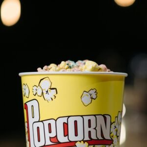 Close-up of colorful popcorn in a bright yellow bucket with a popcorn design.